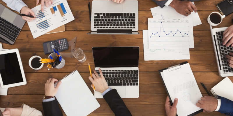 a group of accountants gathered around a table with their laptops