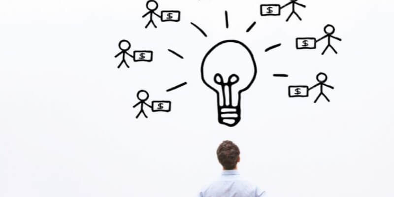 man looking up at whiteboard with lightbulb and stick figures