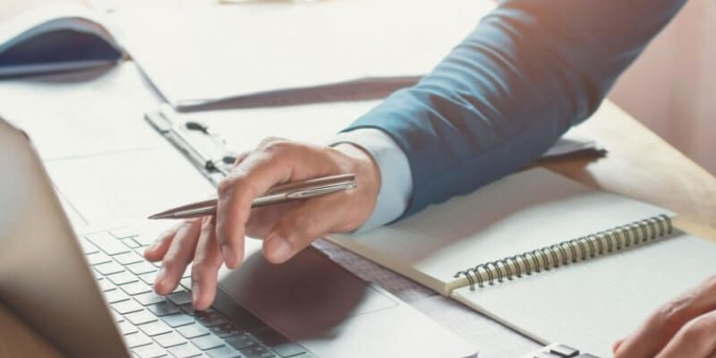 man with notebook open typing on laptop