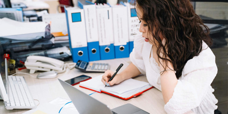 Woman writes notes while using QuickBooks for construction accounting