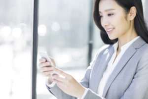 A businesswoman using the QuickBooks mobile app on her smartphone.