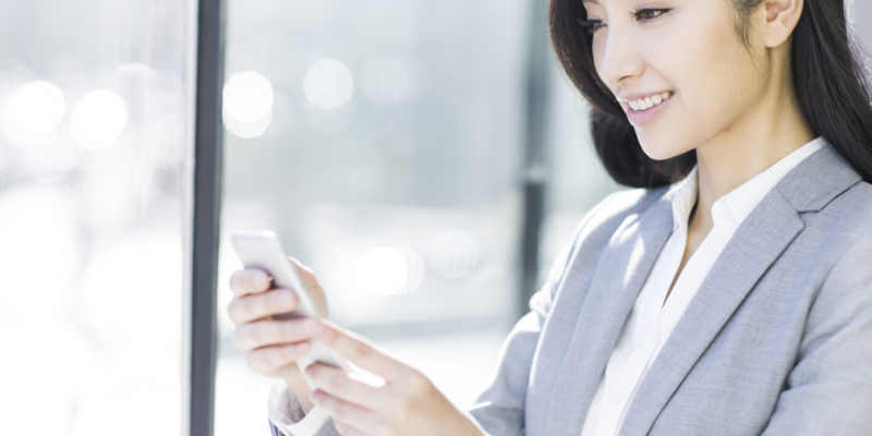 A businesswoman using the QuickBooks mobile app on her smartphone.