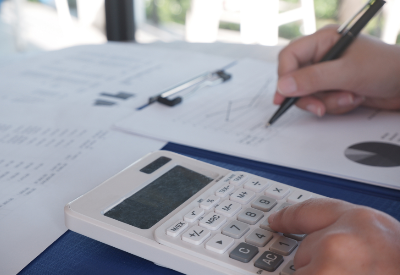 An accountant crunching numbers with a calculator and notepad.