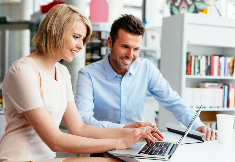 A financial consultant assisting a small business owner on a laptop.